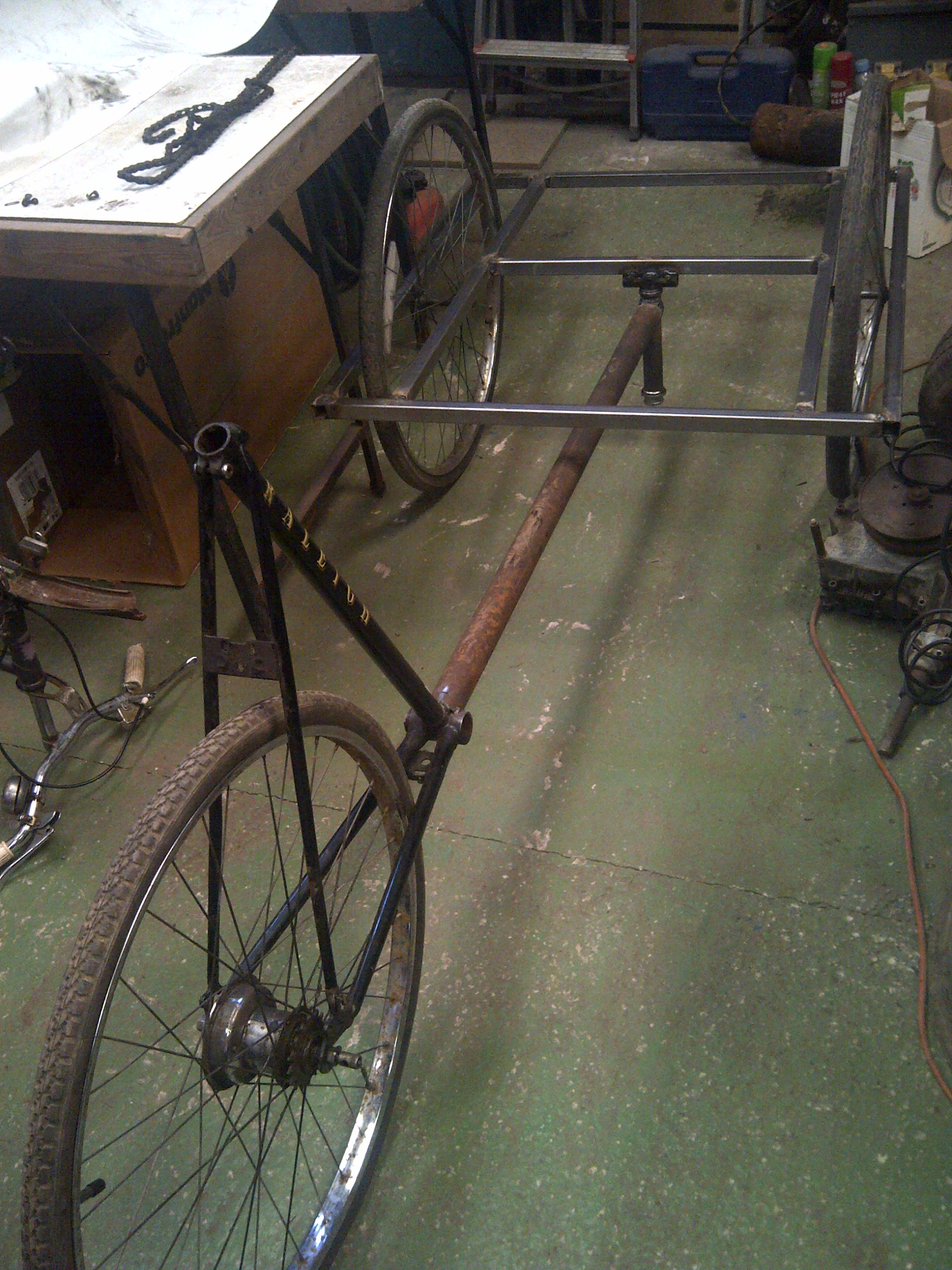 The cargo trike beginning to take shape. The rusty looking main tube I found and attached to the back ebd of the original bike can be seen, as can the upside down head tube forming the pivot. The wheels had just been rested in place for the photo at this stage.
